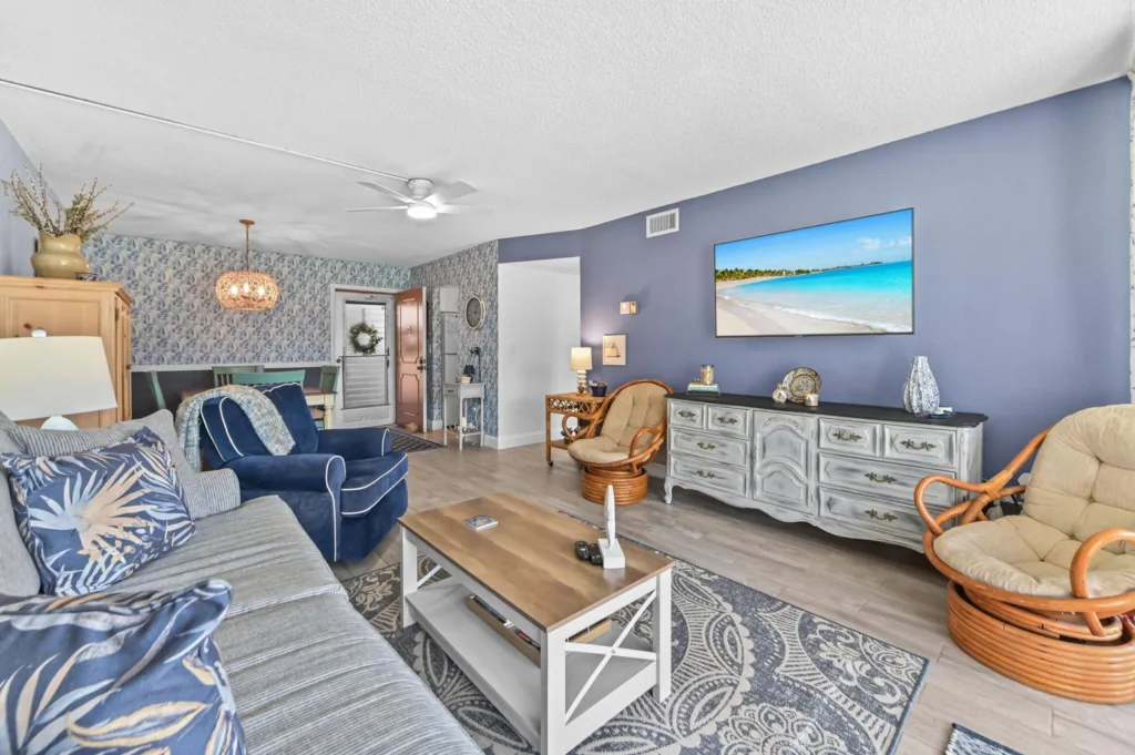20260916183458709089000000-o - Lake Worth Homes - Lake Worth Homes Coastal living room with blue accent wall, white-and-gray furniture, and a large TV above a light cabinet on the right.