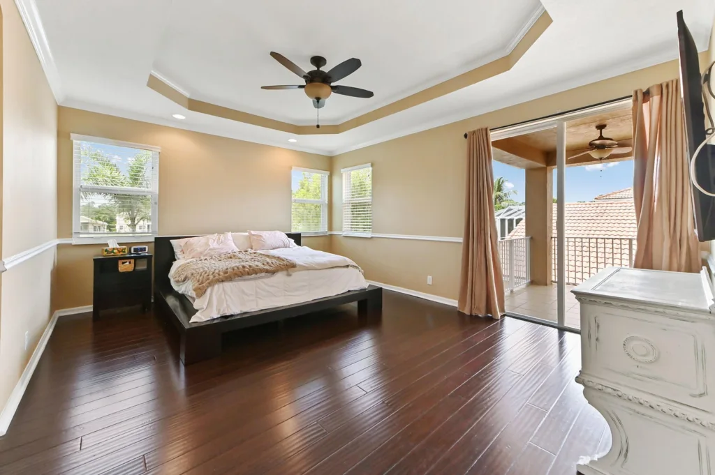 20260922220458789955000000-o - Lake Worth Homes - Lake Worth Homes Bright bedroom with a dark wood platform bed, white bedding, and a beige-plush throw on a dark hardwood floor. two windows on the left wall provide light.