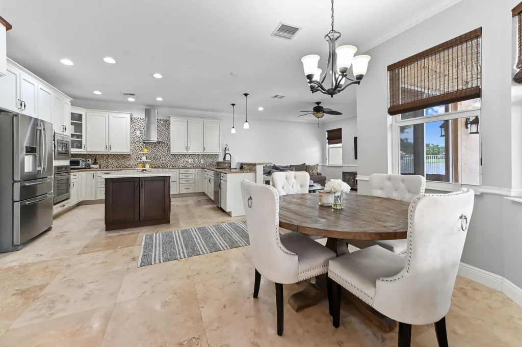 20260922220129513813000000-o - Lake Worth Homes - Lake Worth Homes Open-concept kitchen with white cabinets, stainless steel appliances, mosaic backsplash, and a dark wood island in the center.