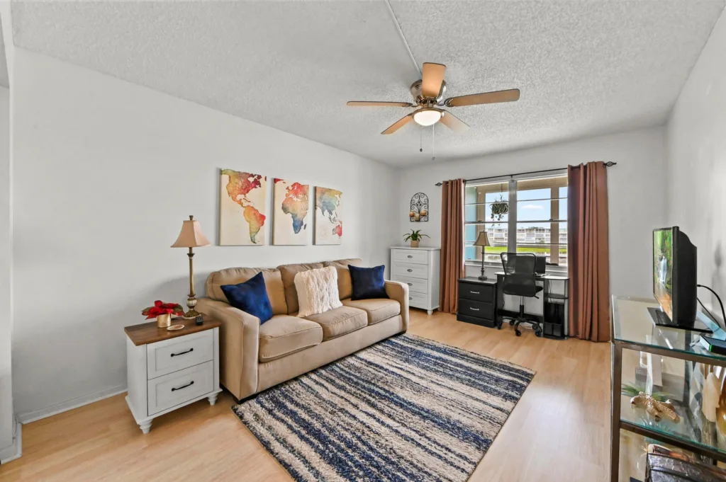 20260929155343677202000000-o - Lake Worth Homes - Lake Worth Homes Cozy living room with beige sofa, blue pillows, and a world map triptych above the couch.