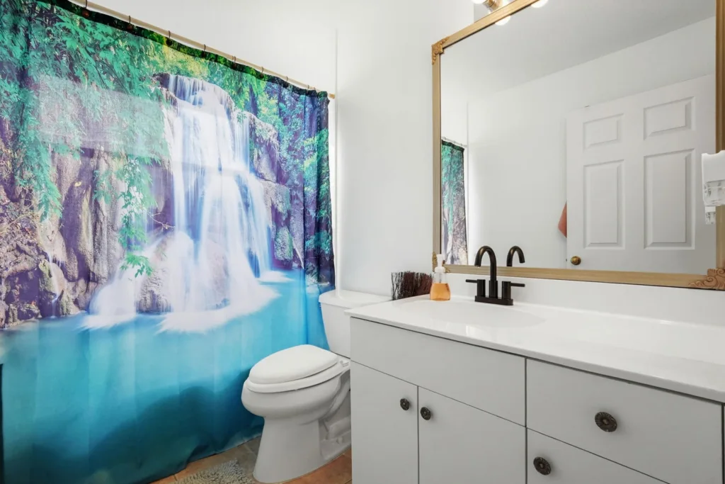 20260924161920030891000000-o - Lake Worth Homes - Lake Worth Homes Bathroom with a nature-themed shower curtain showing a waterfall, white vanity, and black faucet.