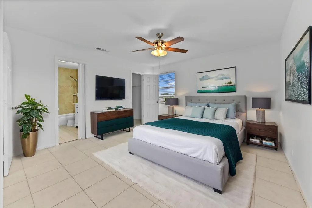 20260930184937039958000000-o - Lake Worth Homes - Lake Worth Homes Bright master bedroom with king bed, teal throw, and bedside lamps; TV on dresser opposite.