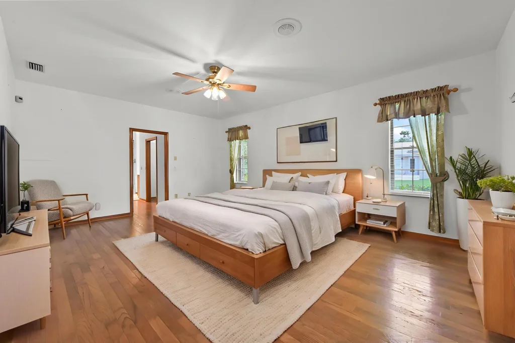 20260930222715245067000000-o - Lake Worth Homes - Lake Worth Homes Bright master bedroom with a large wooden platform bed, two white nightstands, and a light rug on hardwood floors.