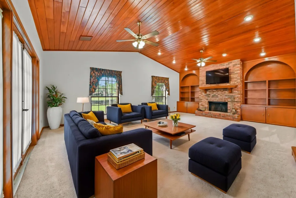 20260930222701559034000000-o 1 - Lake Worth Homes - Lake Worth Homes Cozy living room with navy sofas, yellow cushions, and a wood-paneled vaulted ceiling with ceiling fans.