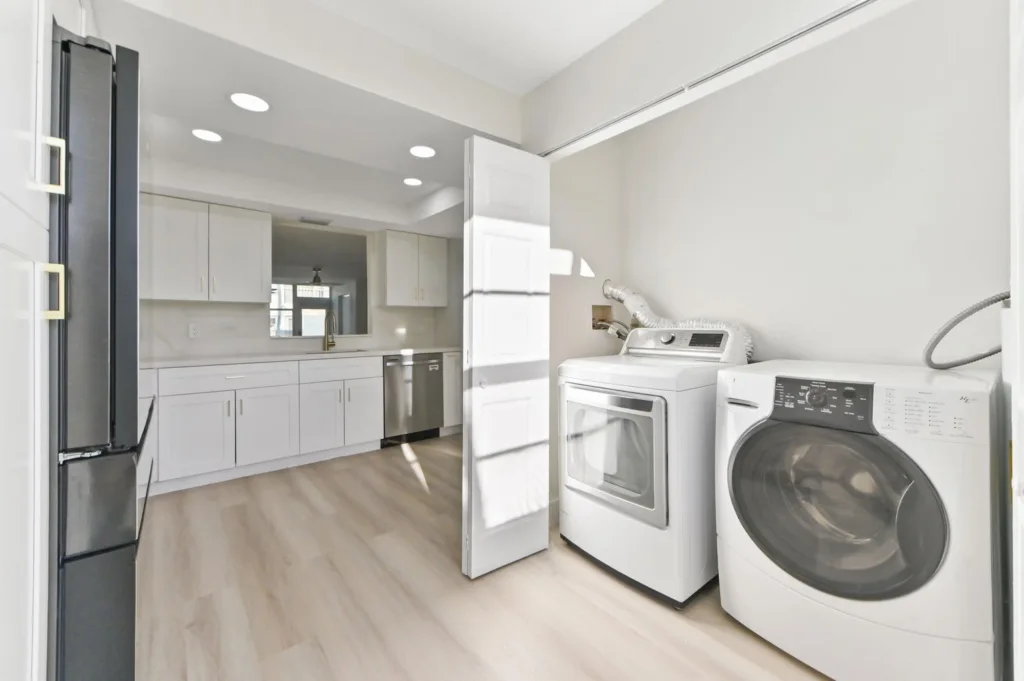 20260929180427539342000000-o - Lake Worth Homes - Lake Worth Homes Bright open laundry room with white cabinets, a black refrigerator on the left, and a front-loading washer and dryer to the right.