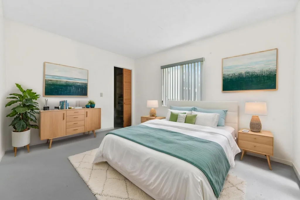 Bright minimalist bedroom with a white bed, aqua bedding, and two wooden nightstands with lamps.