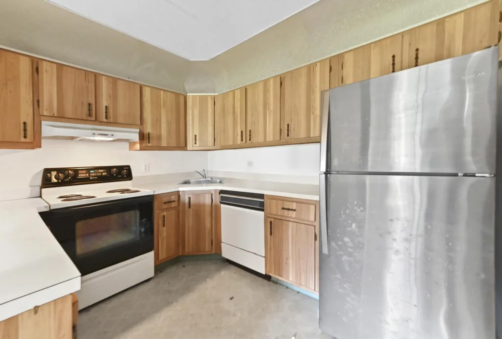 U-shaped kitchen with wooden cabinets, white countertops, and a large stainless steel refrigerator.