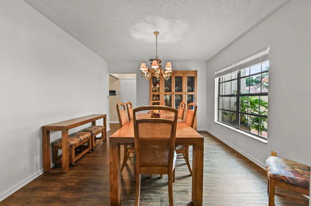 20261002195902004167000000-o - Lake Worth Homes - Lake Worth Homes Dining room with a wooden table and chairs, a chandelier overhead, and a glass-front cabinet against the back wall.