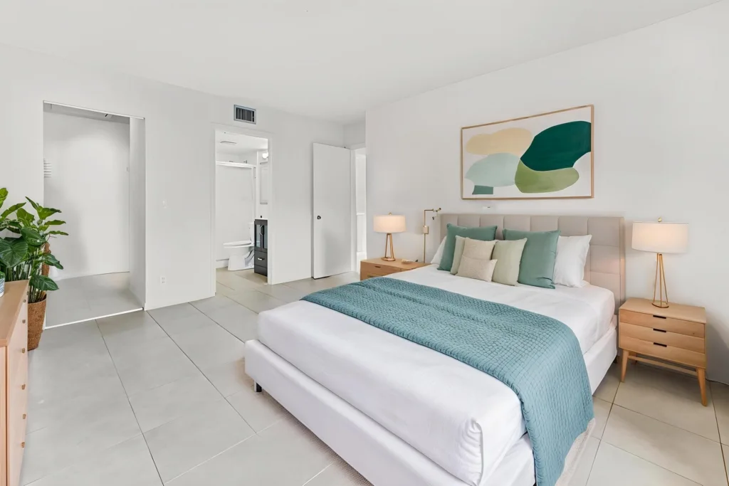 20261007235027686287000000-o - Lake Worth Homes - Lake Worth Homes Bright minimalist bedroom with a king bed, teal throw, and coordinating pillows, plus two wooden nightstands and abstract wall art above the headboard