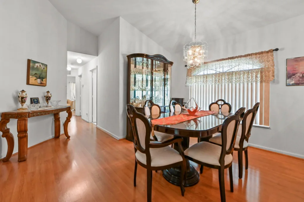 20261006193519352391000000-o - Lake Worth Homes - Lake Worth Homes Elegant dining room with a glass oval table, six upholstered chairs, a crystal chandelier, and a china cabinet.