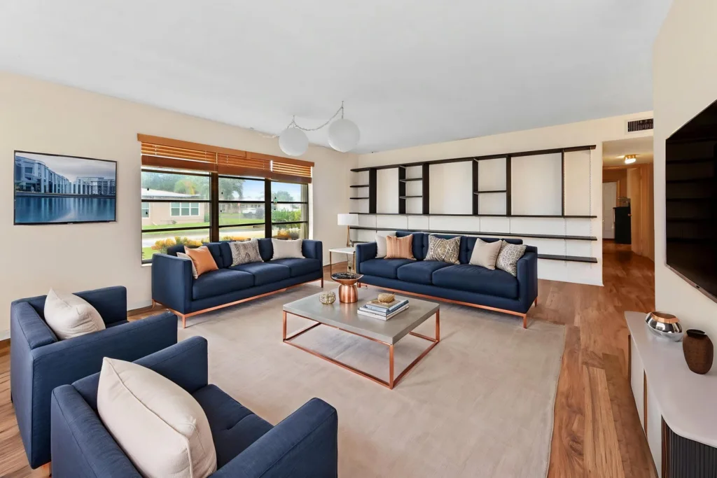 Modern living room with navy sofas, light wood floors, and a large wall shelving unit.