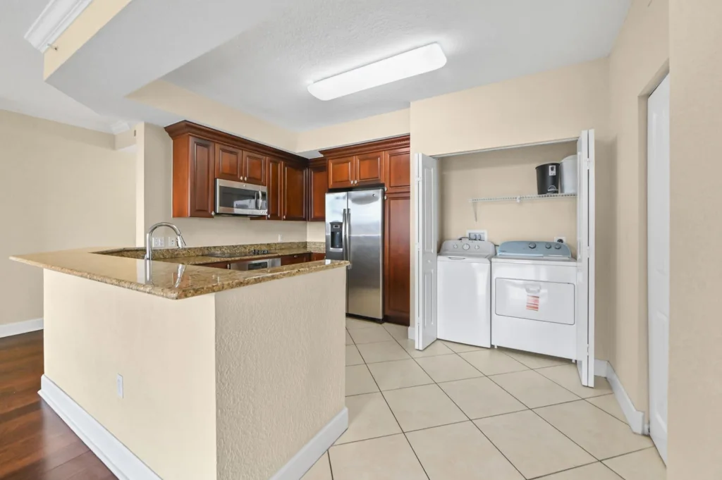 20261007214707067681000000-o - Lake Worth Homes - Lake Worth Homes Kitchen with granite island, dark wood cabinets, and stainless steel refrigerator/microwave.
