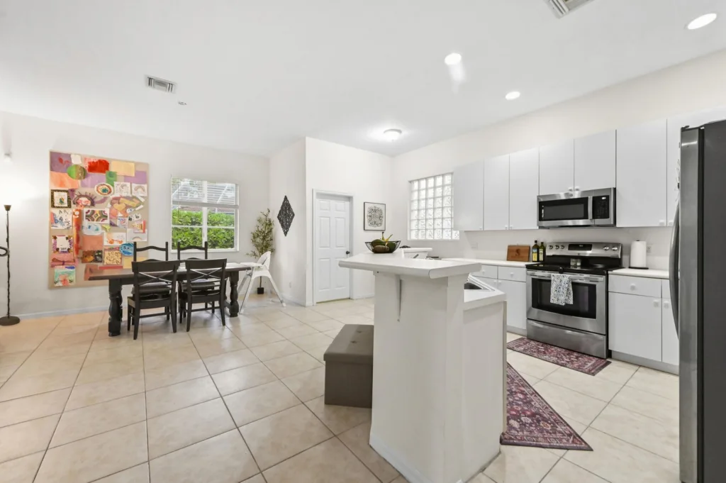 Open-concept kitchen and dining area with white cabinets, a center island, and a colorful wall art piece.