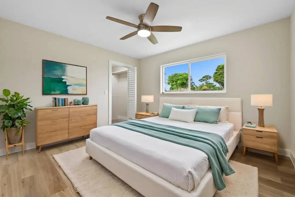 20261021192301107578000000-o - Lake Worth Homes - Lake Worth Homes Bright modern bedroom with a white upholstered bed, mint throw, matching pillows, wooden nightstands, dresser, and a green plant in a pot.
