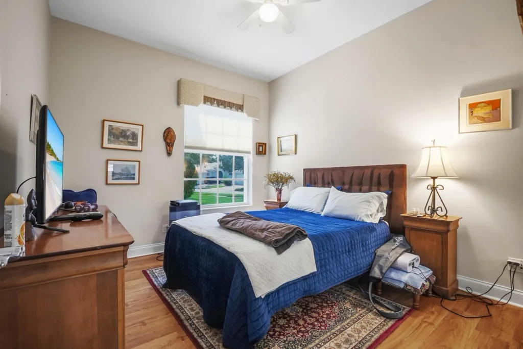 A cozy bedroom with a navy quilted bed, white pillows, and two wooden nightstands under a ceiling fan.