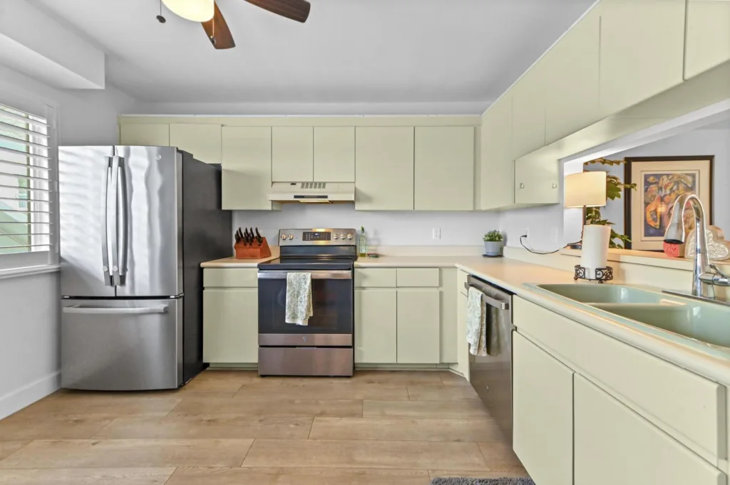 20261022153344404605000000-o - Lake Worth Homes - Lake Worth Homes Bright kitchen with pale green cabinets, stainless steel fridge and stove, and a double-basin sink near an island.