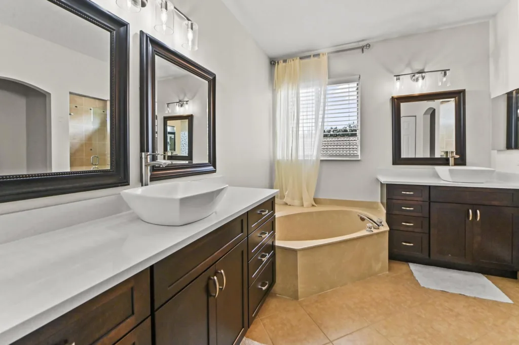 20261019172747702310000000-o - Lake Worth Homes - Lake Worth Homes Modern bathroom with dual dark-wood vanities, white vessel sinks, and large framed mirrors.